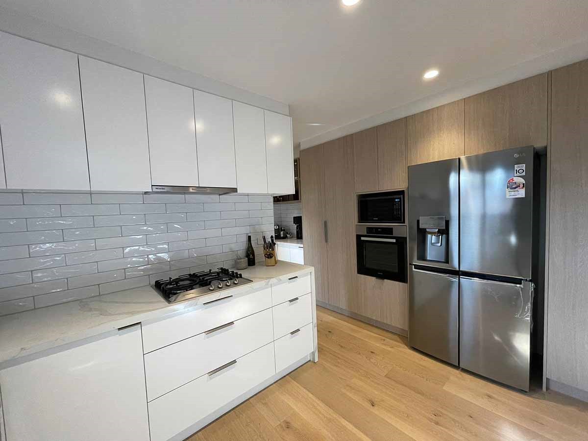 Scandi style kitchen with white cabinets, stainless steel appliances, light wood flooring, and a minimalist design.